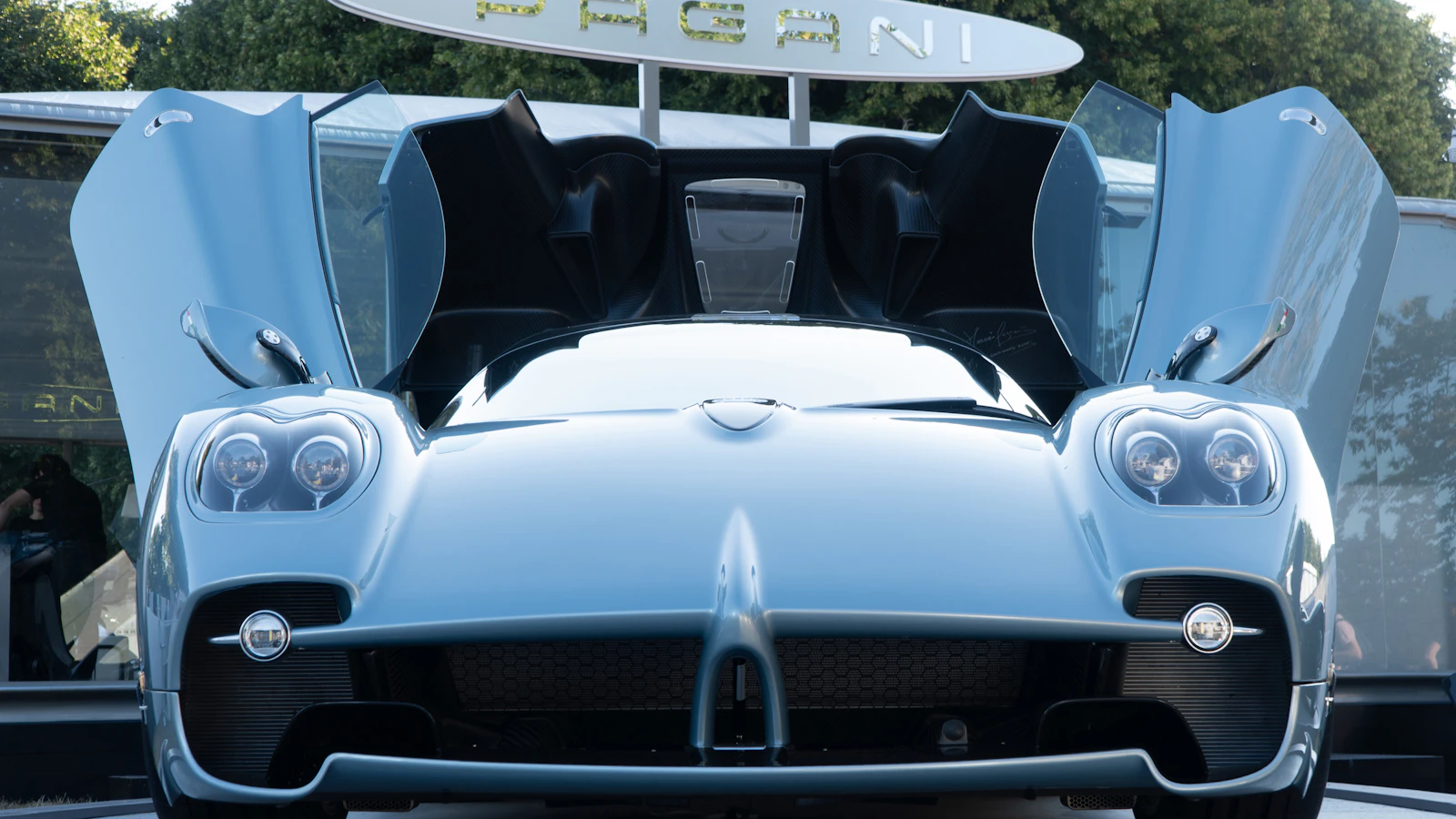 A blue supercar with its doors open in a warm evening setting