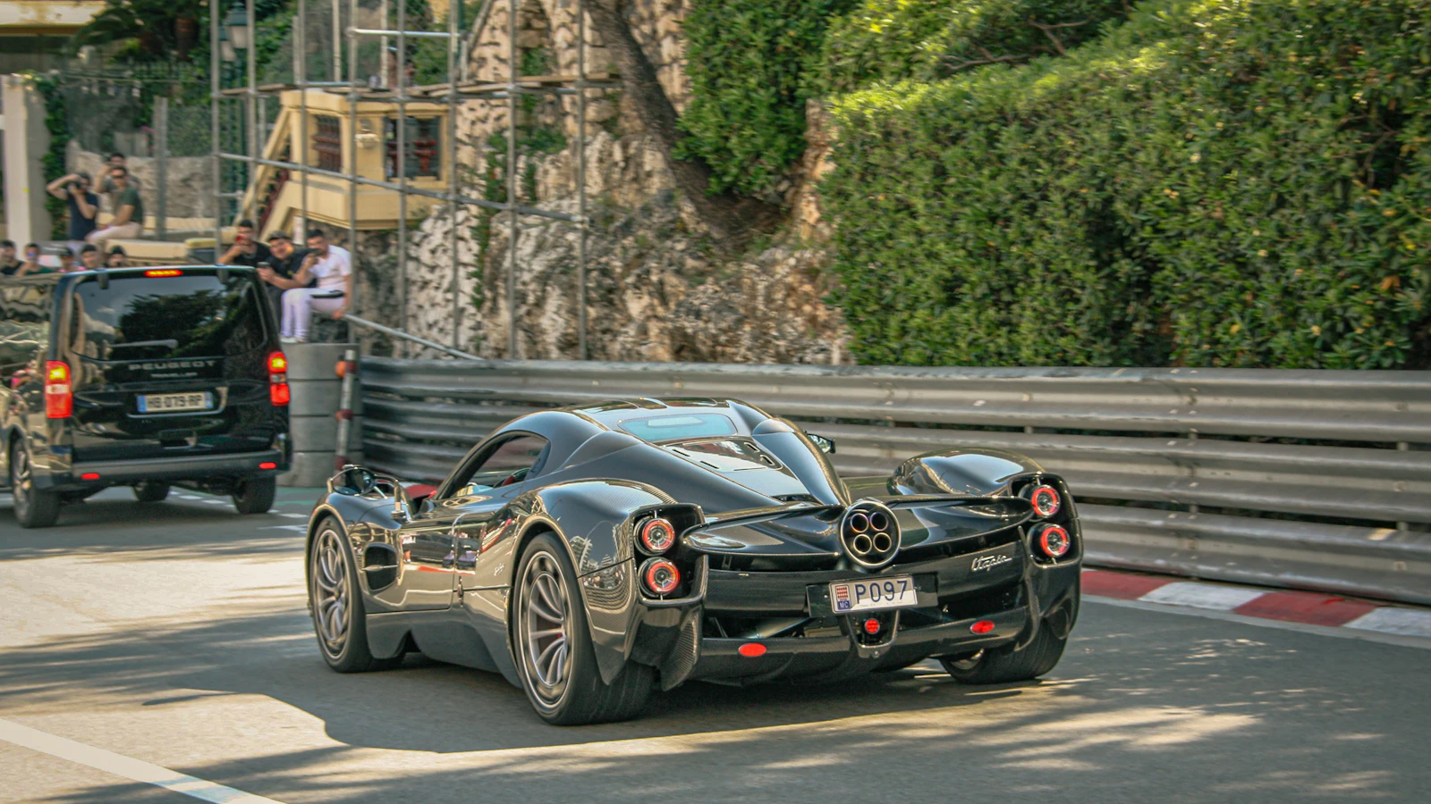 A dark supercar cruising down a city street